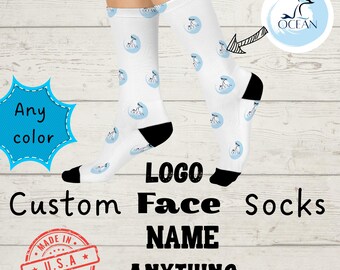 以下が含まれることがあります： 水色の円の中に濃い青色のクジラの尾のロゴが繰り返される模様の白い靴下。かかととつま先は黒色。画像内のテキストには、Any color、LOGO、Custom Face Socks、NAME、ANYTHING、MADE IN U.S.A.が含まれています。