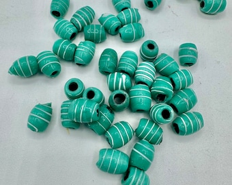 Puede incluir: Una colección de cuentas ovaladas de color verde azulado con rayas blancas. Las cuentas están hechas de madera y tienen un acabado liso y pulido.