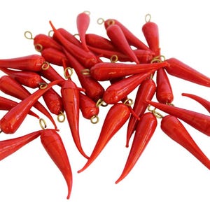 May include: A pile of red chili pepper shaped glass beads with gold-colored metal loops at the top.