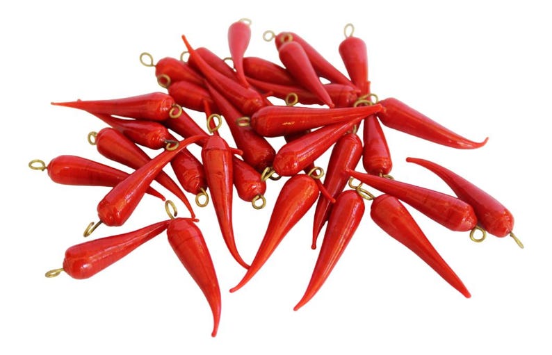 May include: A pile of red chili pepper shaped glass beads with gold-colored metal loops at the top.