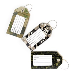 May include: Three luggage tags with different camouflage patterns. Each tag has a clear plastic window for writing name, telephone number, email, and address. The tags are attached to silver metal rings.