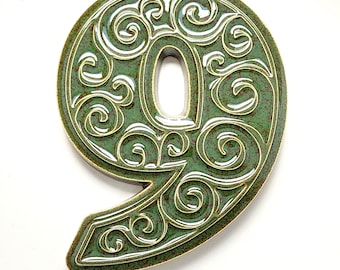 May include: Decorative ceramic number nine in a green and white color scheme. The number has an ornate, swirling design with a glossy finish. The edges are outlined in a contrasting color.