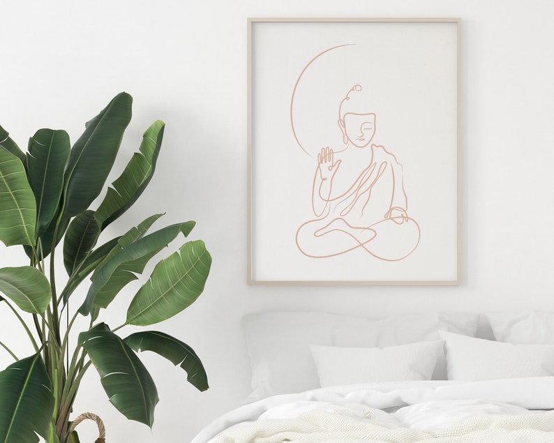 Puede incluir: Un dibujo de l&iacute;nea minimalista de un Buda meditando en color melocot&oacute;n, enmarcado en un marco de madera claro contra una pared blanca.