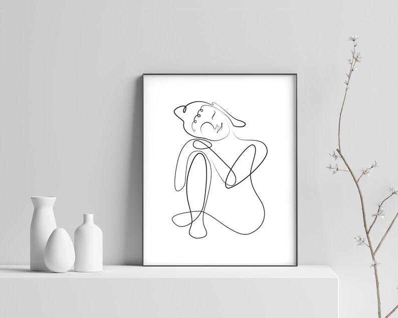 May include: A black and white line drawing of a person sitting with their head resting on their hand. The drawing is in a simple, minimalist style.