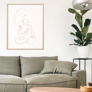 Puede incluir: Un dibujo lineal de un Buda meditando en un estilo minimalista. El dibujo es de color rosa claro y est&aacute; enmarcado en un marco de madera clara.