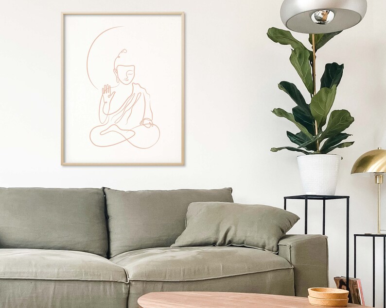 Puede incluir: Un dibujo lineal de un Buda meditando en un estilo minimalista. El dibujo es de color rosa claro y est&aacute; enmarcado en un marco de madera clara.