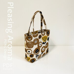 Op de afbeelding: Een witte tote bag met een bruine en gele bloemenprint. De tas heeft een bruine stoffen handvat en een ritssluiting.