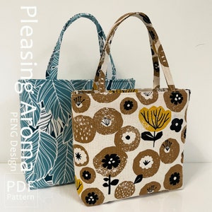 Op de afbeelding: Twee tote bags, een blauwe met een bladmotief en de andere witte met een bruin en geel bloemenmotief. De tassen zijn gemaakt van stof en hebben een eenvoudig ontwerp.