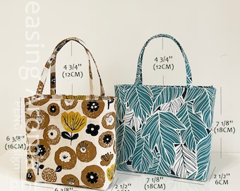 May include: Two tote bags with different fabric patterns. The bag on the left has a brown and white floral pattern. The bag on the right has a blue and white leaf pattern. Both bags have a 4 3/4 inch handle height and are 6 3/8 inches wide and 7 1/8 inches tall.