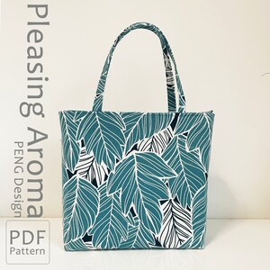 Op de afbeelding: Een teal-kleurige tote bag met een wit en zwart bladmotief. De tas heeft twee handvatten en is gemaakt van stof. De tekst "Pleasing Aroma PENG Design PDF Pattern" is gedrukt aan de linkerkant van de afbeelding.