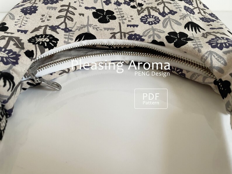 May include: A close-up of a beige fabric bag with a black and white floral print. The bag has a zipper closure and the text "Pleasing Aroma PENG Design PDF Pattern" is visible.
