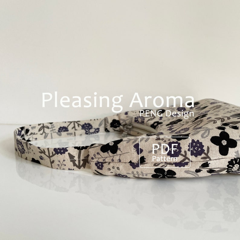 May include: A beige fabric handbag with a black floral print and a black strap. The bag has a zipper closure and the text "PDF Pattern" is printed on the front of the bag.