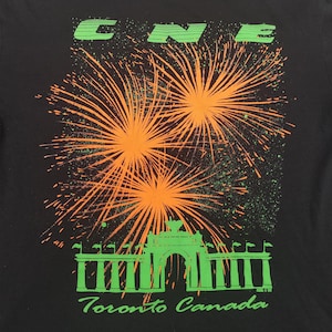 May include: Black t-shirt with a green and orange graphic of fireworks over a green archway with the text "Toronto Canada".