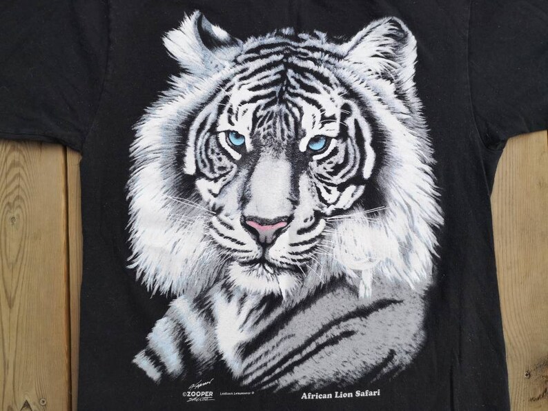Może przedstawiać: Czarny T-shirt z grafiką białego tygrysa i tekstem "African Lion Safari".