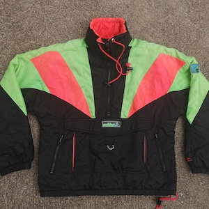 May include: A black, green and pink vintage ski jacket with a half-zip closure and a small logo on the upper right sleeve. The jacket has a large pocket on the front with a drawstring.