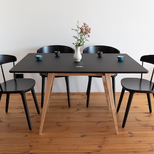 Small extended dining table with wooden legs and black top. Ausgeklappt Kleiner Esstisch mit Holzbeinen und schwarzener Platte  Deplié petite table à manger avec pieds en bois et plateau noir avec système d'extension simple.