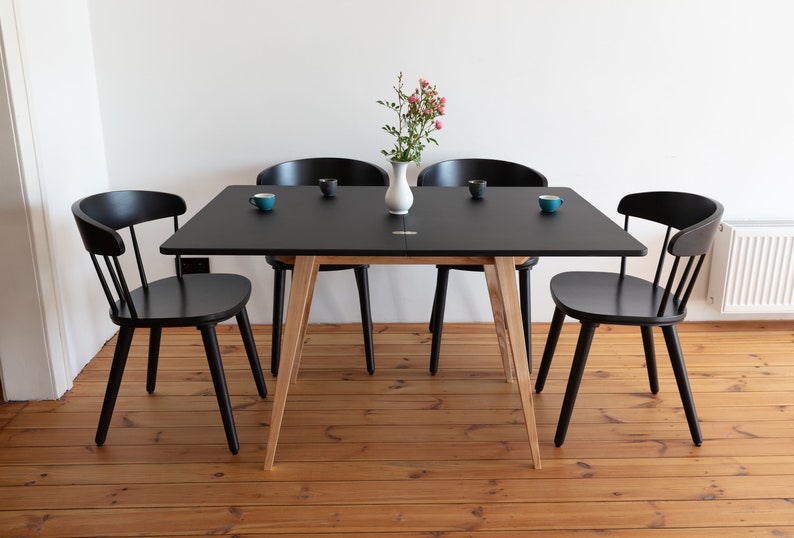 Small extended dining table with wooden legs and black top. Ausgeklappt Kleiner Esstisch mit Holzbeinen und schwarzener Platte  Deplié petite table à manger avec pieds en bois et plateau noir avec système d'extension simple.