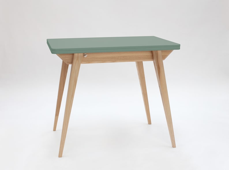 Small extendable dining table with wooden legs and grey-green top. Kleiner Esstisch mit Holzbeinen und graugrüner Platte mit einfachem Verlängerungssystem. Petite table à manger avec pieds en bois et plateau gris-vert