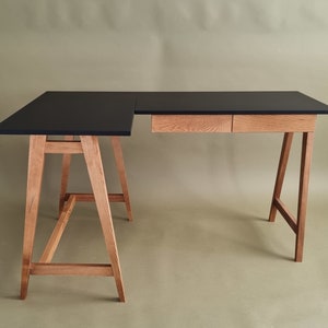 L-foermiger Schreibtisch mit Holzbeinen und zwei Holzschubladen und schwarz mat Platte. Bureau en forme de L avec pieds en bois et deux tiroirs en bois et plateau noir. L-vormig bureau met houten poten en twee houten lades en  zwart blad