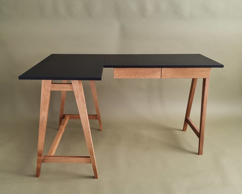 L-foermiger Schreibtisch mit Holzbeinen und zwei Holzschubladen und schwarz mat Platte. Bureau en forme de L avec pieds en bois et deux tiroirs en bois et plateau noir. L-vormig bureau met houten poten en twee houten lades en  zwart blad