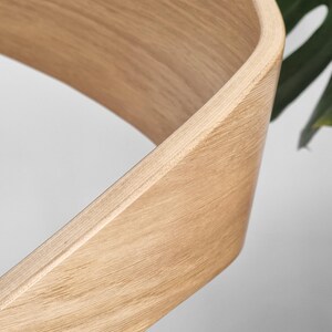 May include: Close-up of a light brown wooden chair back with a curved design.