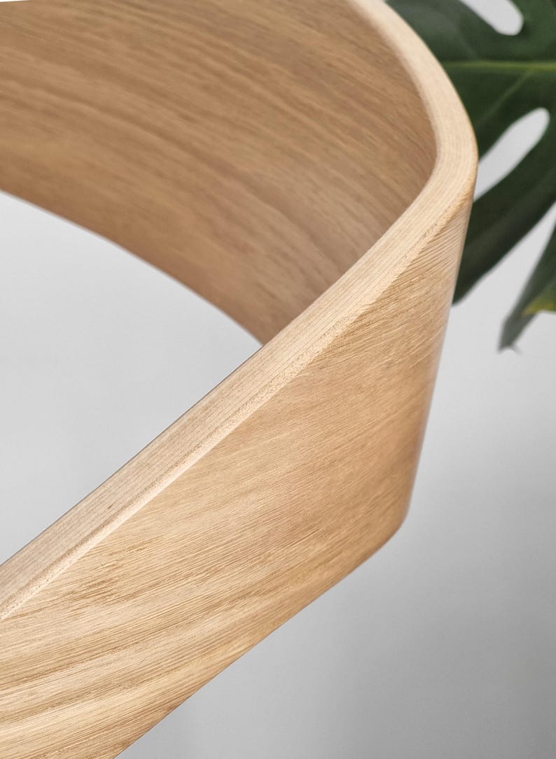 May include: Close-up of a light brown wooden chair back with a curved design.