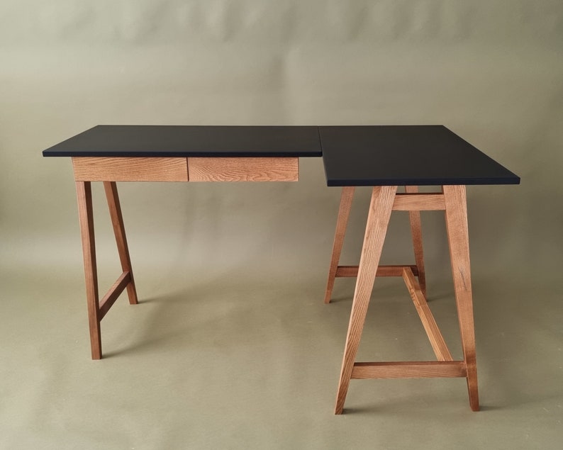 L-foermiger Schreibtisch mit Holzbeinen und zwei Holzschubladen und schwarz mat Platte. Bureau en forme de L avec pieds en bois et deux tiroirs en bois et plateau noir. L-vormig bureau met houten poten en twee houten lades en  zwart blad