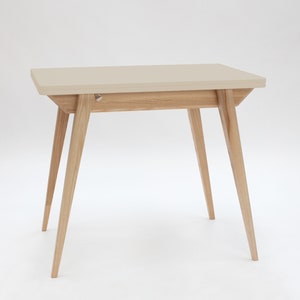 Small extendable dining table with wooden legs and chalk white top. Kleiner Esstisch mit Holzbeinen und creme weiss Platte mit einfachem Verlängerungssystem. Petite table à manger avec pieds en bois et plateau blanc craie.