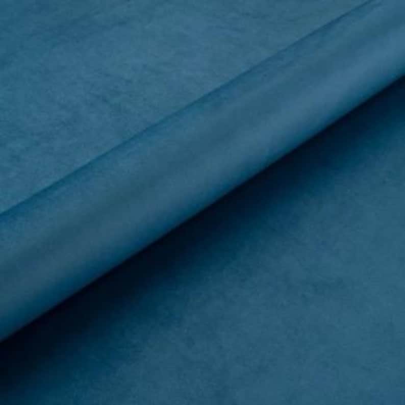 May include: A close-up of a solid teal blue fabric. The fabric has a soft, velvety texture.