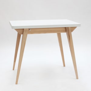 Small extendable dining table with wooden legs and white top. Kleiner Esstisch mit Holzbeinen und weisseer Platte mit einfachem Verlängerungssystem. Petite table à manger avec pieds en bois et plateau blanc avec système d'extension simple.