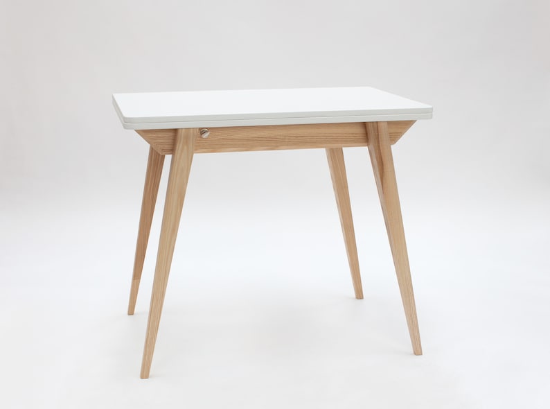 Small extendable dining table with wooden legs and white top. Kleiner Esstisch mit Holzbeinen und weisseer Platte mit einfachem Verlängerungssystem. Petite table à manger avec pieds en bois et plateau blanc avec système d'extension simple.