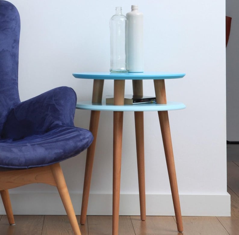 Small end table with wooden legs and blue tops. Kleiner Couchtisch mit Holzbeinen und blauen Tischplatten. Petite table basse avec des pieds en bois et des plateaux bleus.