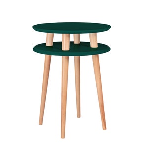 Puede incluir: Una mesa auxiliar redonda de dos niveles con una tapa de color verde oscuro y patas de madera natural.