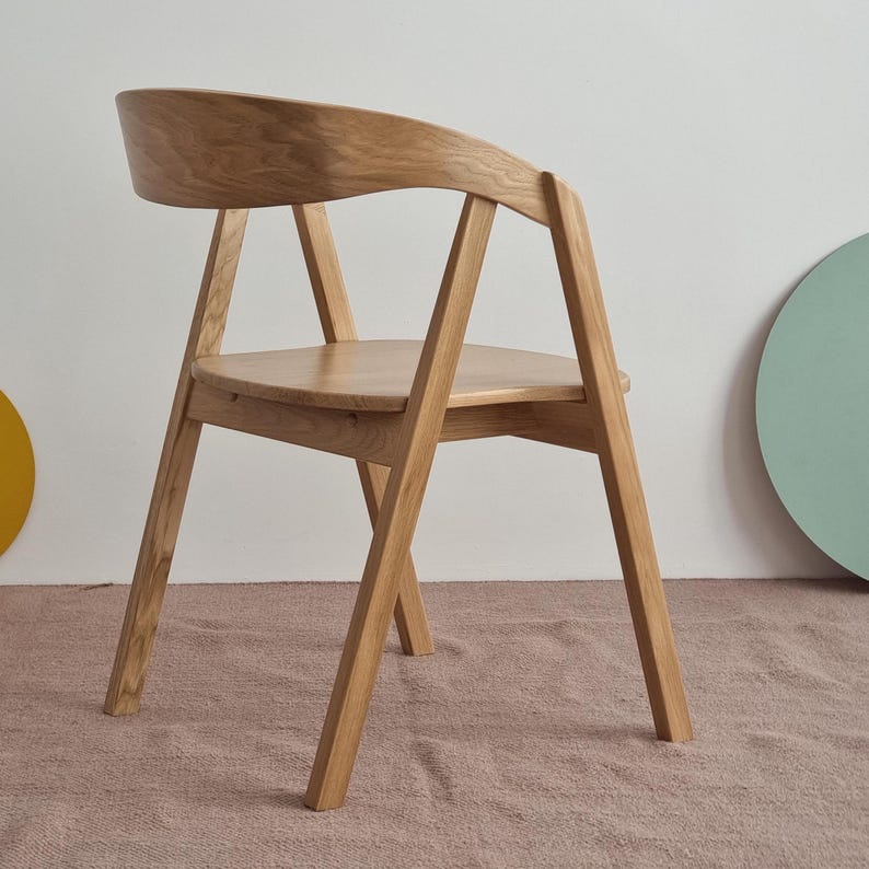 May include: A wooden chair with a curved back and a simple design. The chair is made of light brown wood and has a natural finish.