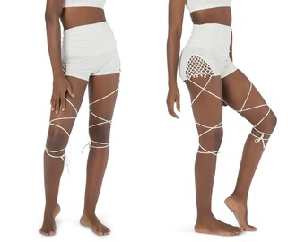 Puede incluir: Un conjunto blanco de dos piezas con un top corto blanco y pantalones cortos blancos. Los pantalones cortos tienen un diseño de cordones en las piernas.
