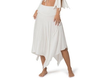 May include: A white crop top with a V-neck and cold shoulder design. The top has a tie at the front and bell sleeves. The model is also wearing a white, asymmetrical skirt.