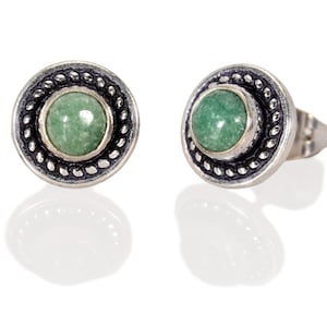 Op de afbeelding: Een paar zilveren oorbelletjes met groene edelsteen accenten. De oorbelletjes hebben een rond ontwerp met een parelrand.