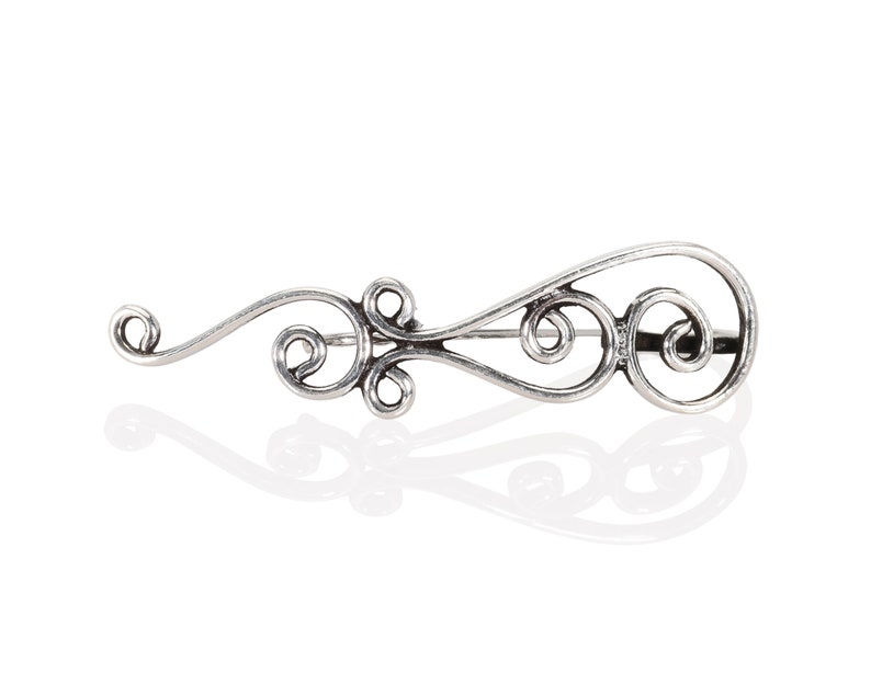 May include: A silver brooch with a delicate, swirling design. The brooch is made of metal and has a polished finish.