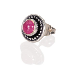 May include: A silver earring with a pink gemstone set in a decorative silver bezel.