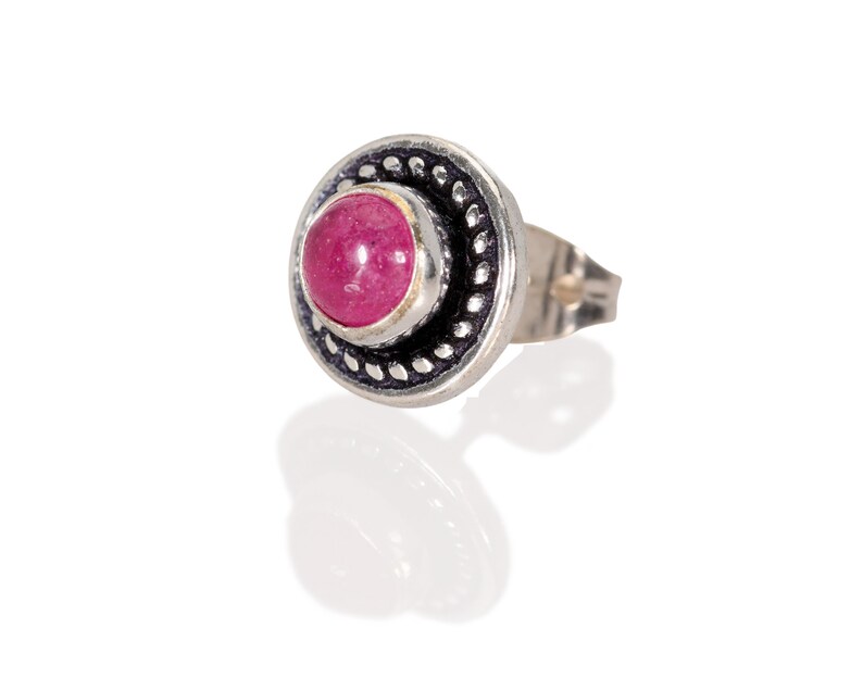 May include: A silver earring with a pink gemstone set in a decorative silver bezel.