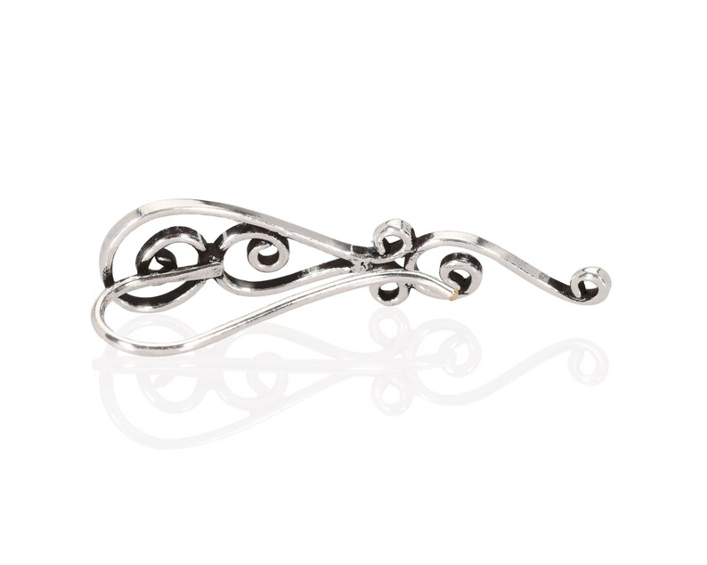 May include: Silver filigree earring with a delicate, curved design. The earring has a hook closure.