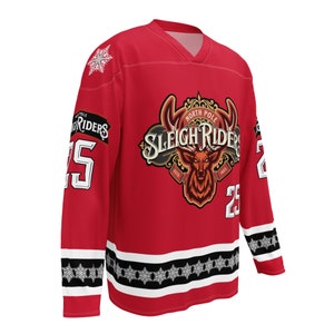 May include: Red hockey jersey with a white snowflake design on the shoulders and a white and black snowflake stripe around the bottom. The jersey has a large logo on the front that says "North Pole Sleigh Riders" with a deer head in the center. The number "25" is on both sleeves.