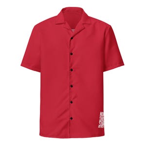 May include: A bright red short-sleeved button-down shirt with a classic collar. The shirt has black buttons and a white logo on the lower right side. The shirt is made of a smooth, likely synthetic fabric.