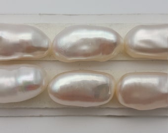 May include: Six white oval-shaped pearls arranged in two rows of three on a white surface. The pearls have a slight iridescent sheen. The number "3" is written on a white square below the pearls.