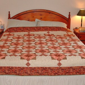 May include: A white and brown quilt with a diamond pattern on a wooden bed frame with a white headboard. The bed has two nightstands with lamps on each side.