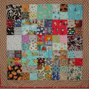 May include: A colorful patchwork quilt with a variety of patterns, including animals, numbers, letters, and cartoon characters. The quilt is made up of many small squares, each with a different design. The quilt is bordered with a red and orange wavy trim.