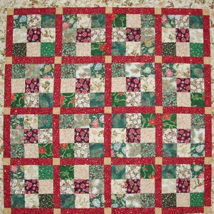 May include: A Christmas quilt with a red, green, and white patchwork design. The quilt is made up of squares with different patterns, including snowflakes, ornaments, and holly.