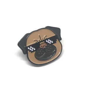 Peut inclure: Une &eacute;pingle en &eacute;mail marron et noir repr&eacute;sentant un carlin portant des lunettes de soleil &agrave; motif &agrave; carreaux. Le carlin a un nez noir et des yeux noirs.