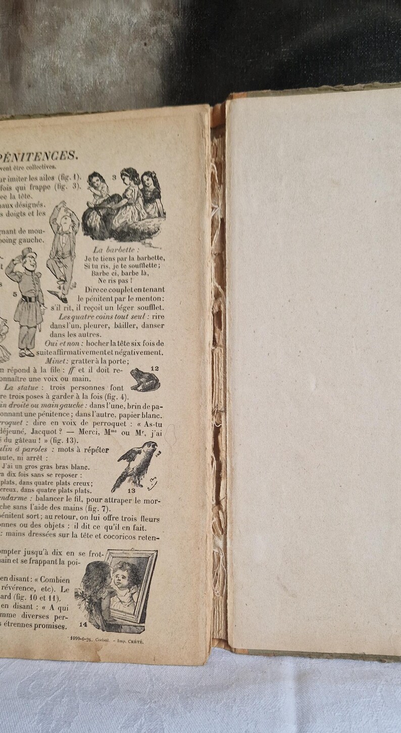 May include: Open book with aged pages featuring illustrations and French text. The left page has drawings of people and animals, with text in a vintage font. The right page is blank.
