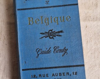 May include: A blue guide book with the title "Guides Pratiques Conty" and "Belgique" in gold lettering. The book also features the text "Guide Conty" and "12, Rue Auber, 12 Paris".